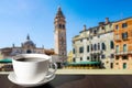 Cup of black coffee on the table with view of Italian square in Venice with tower and colorful buildings in Venice, Italy