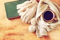 Cup of black coffee with a warm scarf and old book on wooden background. filreted image.