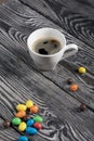 A cup of black coffee in a white cup. Chocolate candy in glaze. On pine boards Royalty Free Stock Photo