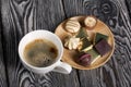 A cup of black coffee in a white cup. Chocolate in foil and chocolates. On pine boards