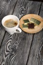 A cup of black coffee in a white cup. Chocolate in foil. On pine boards