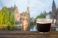 Cup of black coffee on wooden table with view on old town and Belfry tower, Bruges Royalty Free Stock Photo