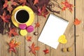 Cup with black coffee, yellow lollipops, macaroons, textile scarf, notepad, wooden table with autumn fallen orange leaves Royalty Free Stock Photo