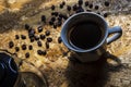 Cup of black java coffee and coffee beans on wooden background, top view