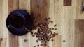 Cup of black morning coffee and cofee beans scattered on brown wooden table