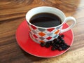 A cup of black morning coffee, raw coffee beans on wooden table. Fresh morning coffee drink concept. Copy space.