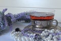 A Cup of black tea on the background of lavender and jewelry-pearls, lilac beads and rings