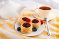 Cup of black tea with danish pastry cake with cranberry jam and fresh blueberry and raspberry on the table. Sunny breakfast Royalty Free Stock Photo