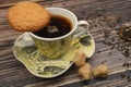 A Cup of black tea, tea leaves, pieces of brown sugar, oatmeal cookies on a wooden background. Close up Royalty Free Stock Photo