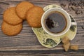 A Cup of black tea, tea leaves, pieces of brown sugar, oatmeal cookies on a wooden background. Close up Royalty Free Stock Photo