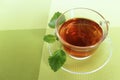 A Cup of black tea and a mint leaf in a glass Cup on a light green background. The view from the top. Royalty Free Stock Photo