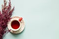 Cup of black tea with pink misty blue dry flowers on sky blue background