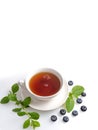 A Cup of black tea on a saucer with mint leaves and blueberries on a white isolated background. Royalty Free Stock Photo