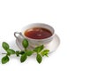 A Cup of black tea on a saucer with mint leaves on a white isolated background. Royalty Free Stock Photo