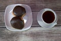 A cup of black tea on a saucer and a plate with two donuts in chocolate icing lie on a wooden table. Close-up Royalty Free Stock Photo