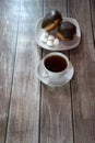 A cup of black tea on a saucer and a plate with two donuts in chocolate icing and pieces of bizet, lie on a wooden table. Close-up Royalty Free Stock Photo