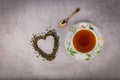 Cup of black tea, small antique spoon and heart-shaped scattered tealeaves Royalty Free Stock Photo