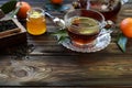 Cup of black tea, tea leaves, honey and tangerines.