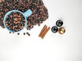 Cup of blue coffee, with coffee beans surrounding, and three cinnamon sticks and three coffee capsules, with white background..Top Royalty Free Stock Photo