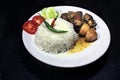 Cup of boiled rice with chicken broth on a white plate isolated on black background. Royalty Free Stock Photo