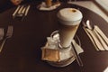 Cup of caffe latte in coffeehouse on brown table with set of cutlery Royalty Free Stock Photo