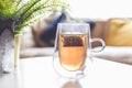 Cup of calming herbal tea with bag in home interior setting