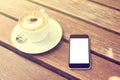 Cup of cappuccino and blank cell phone