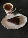 Cup of cappuccino and chocolate cherry pie on white plate on black background Royalty Free Stock Photo