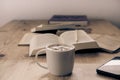 cup with cappuccino coffee accompanied by a series of books and a cell phone on a rustic wooden table Royalty Free Stock Photo