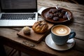 A cup of cappuccino, coffee and breakfast pastries on a wooden table with a laptop computer for work Royalty Free Stock Photo