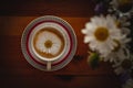 Cup of cappuccino coffee and croissant / brioche on a wooden table with freshly gathered daisy flowers. Italian breakfast. Royalty Free Stock Photo