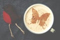 Cup of cappuccino coffee with foam in the form of butterfly on b