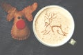 Cup of cappuccino coffee with foam in the form of reindeer on bl
