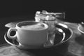 A cup of cappuccino coffee and sugar in a glass vase on a table in a cafe. Black and white photography Royalty Free Stock Photo