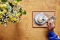 Cup of cappuccino coffee hand with spoon fresh flowers Royalty Free Stock Photo