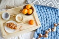 Cup with cappuccino, croissant, blue pastel giant plaid, bedroom, morning concept