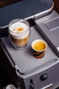 Cup of cappuccino and a cup of espresso are standing on top of an office coffee machine. Inexpensive  simple coffee machine model Royalty Free Stock Photo