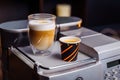 Cup of cappuccino and a cup of espresso are standing on top of an office coffee machine. Inexpensive  simple coffee machine model Royalty Free Stock Photo