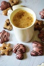 Cup with cappuccino and ginger cookies with sugar glaze on a white wooden table