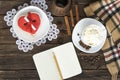 Cup of cappuccino, heart shaped cookies width message, notebook, pencil and coffee pots on a brown wooden table