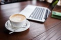Cup of cappuccino and laptop on the table Royalty Free Stock Photo