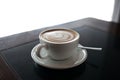 Cup of cappuccino with latte art on black table background. Beautiful foam, place for text.