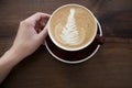 Cup of cappuccino with latte art on wooden table background.