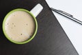 Cup of cappuccino, paper notepad, pen, and on the wooden background.