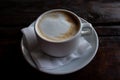 Cup of cappuccino and piece of cake on black wooden table. Cup of coffee with milk foam and dessert on dark background. Royalty Free Stock Photo