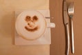 Cup of cappuccino with a smile of cinnamon on a white saucer and beige tablecloths Royalty Free Stock Photo