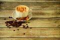 A cup of cappuccino with a sprinkle on the foam in a saucer decorated with cinnamon sticks and star anise is on the table in a Royalty Free Stock Photo