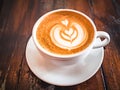 A cup of cappuccino on a table in a cafe. Beautiful plant drawing Leaf on Latte coffee froth. View from above. Delicious Royalty Free Stock Photo