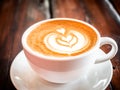 A cup of cappuccino on a table in a cafe. Beautiful plant drawing Leaf on Latte coffee froth. View from above. Delicious Royalty Free Stock Photo