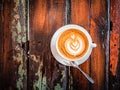 A cup of cappuccino on a table in a cafe. Beautiful plant drawing Leaf on Latte coffee froth. View from above. Flat lay Royalty Free Stock Photo